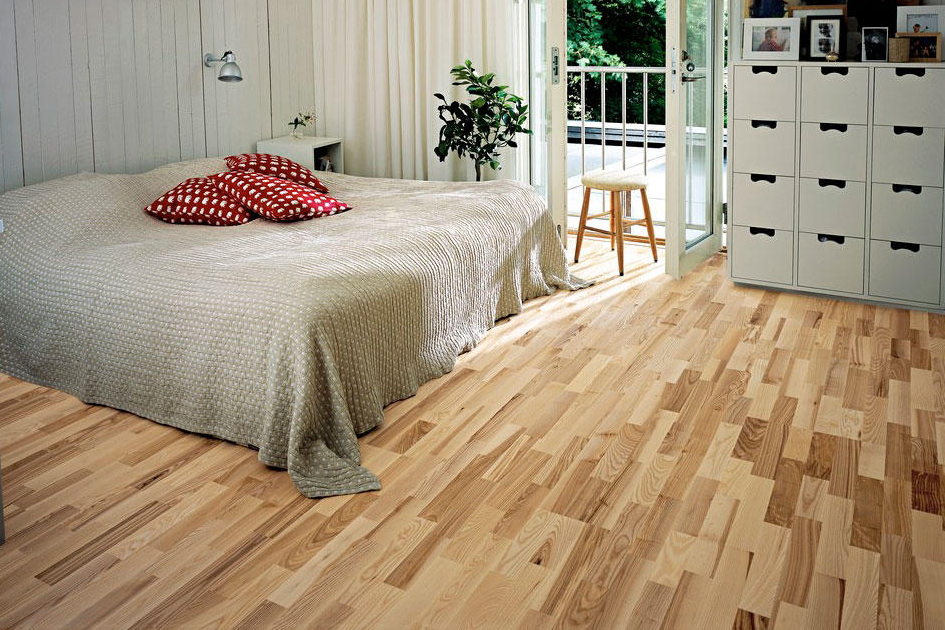 Gray bed on the parquet floor of the bedroom