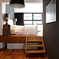 Boxes with things under the podium with a bed.