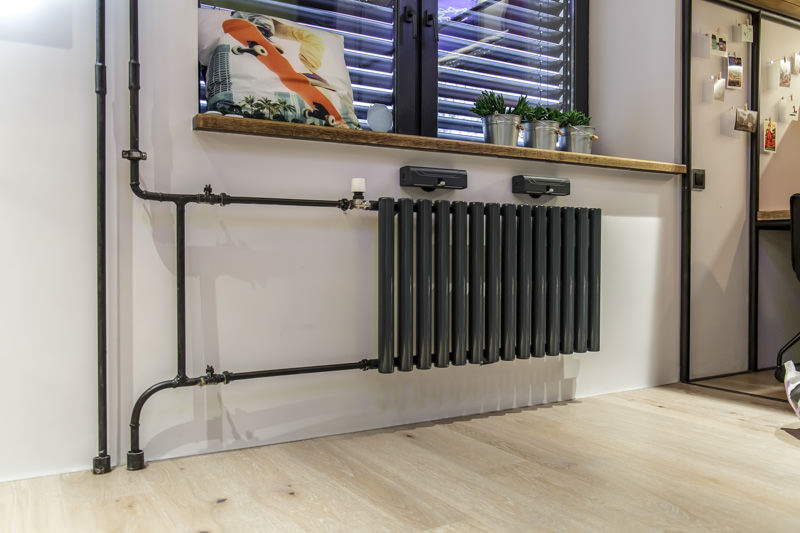 Tuyaux de chauffage noirs sur un fond de mur blanc